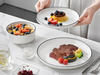 Minimalistyczny zestaw obiadowy z białej porcelany w czarnej oprawie